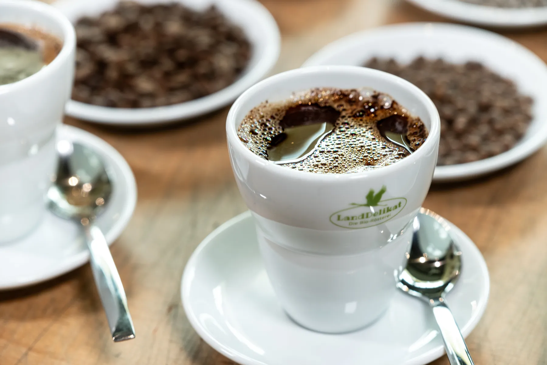 Ein Bio-Rösterei LandDelikat Kaffeebecher gefüllt mit Kaffee.
