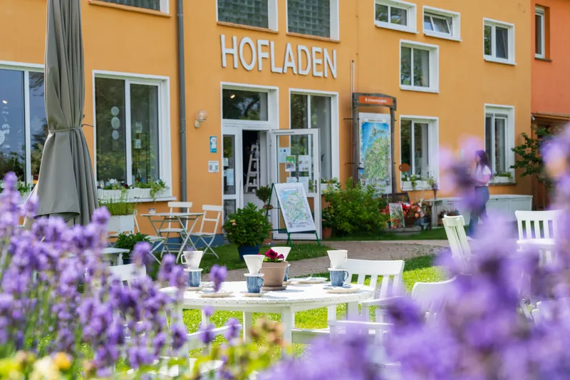 Die Ostseemühle Langenhanshagen von außen: Ein markantes orangenes Gebäude und davor ein gedeckter Kaffeetisch.