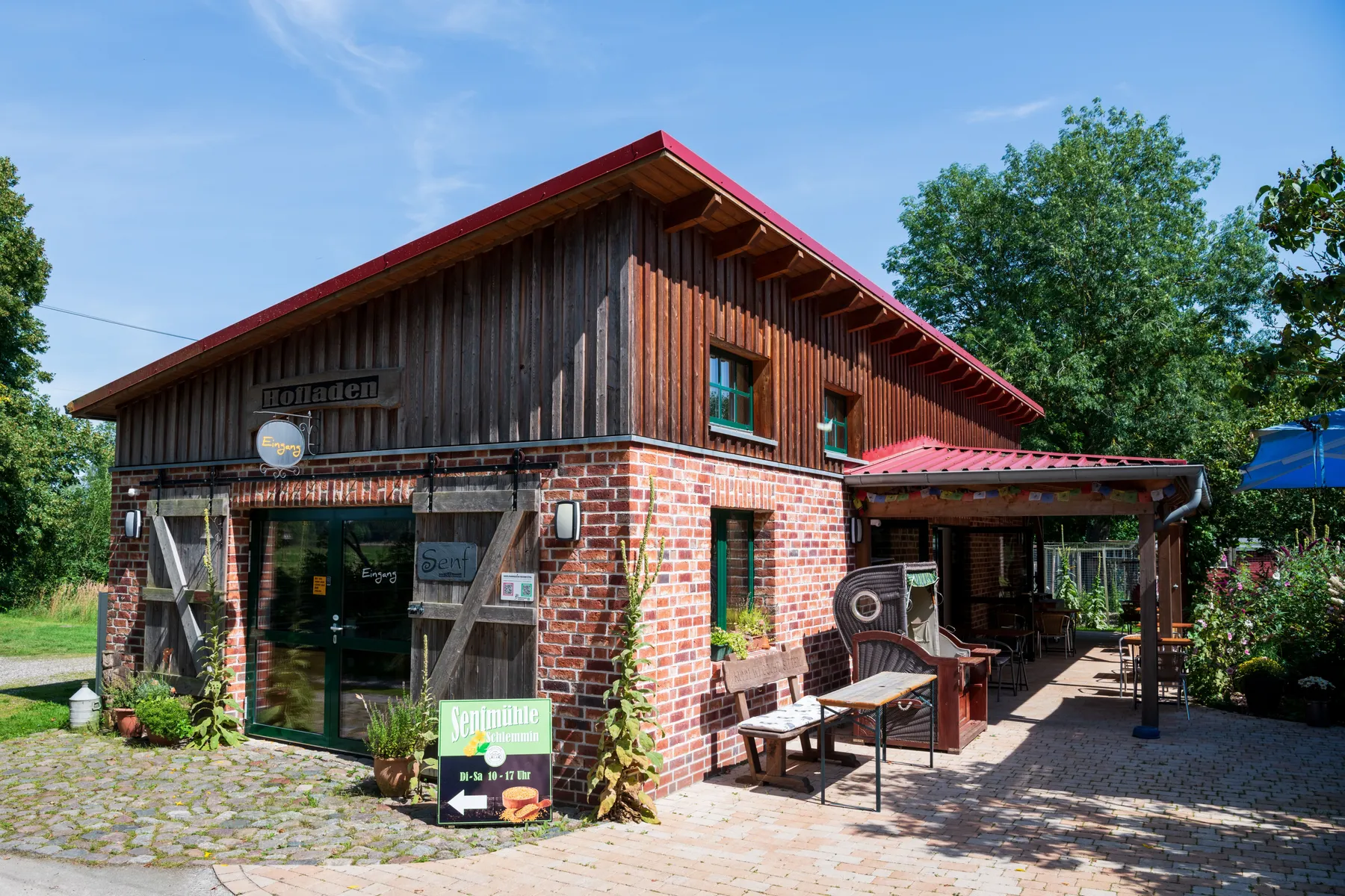 Außenansicht der Senfmühle Schlemmin – ein Backstein- und Holzgebäude mit Terrasse.